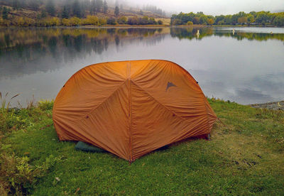 Scenic view of tent on field by lake