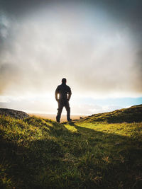 Rear view of man standing on field against sky