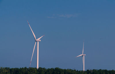 Wind turbines on field against clear blue sky