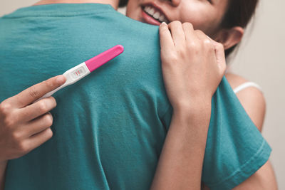 Woman holding pregnancy test while embracing man