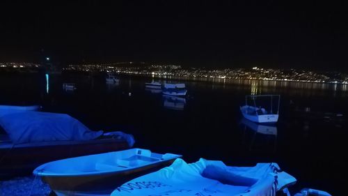 Illuminated city by lake against clear blue sky at night