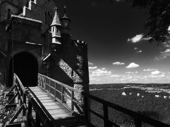 Low angle view of bridge by building against sky