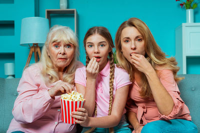 Surprised family watching movie while eating popcorn at home