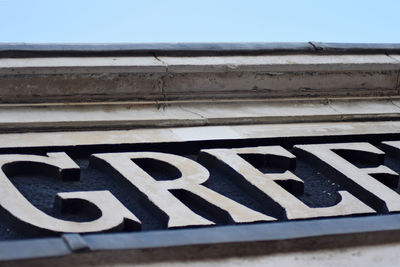 Close-up of text on railing against sky