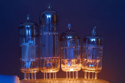 Close-up of illuminated bottles on table against black background