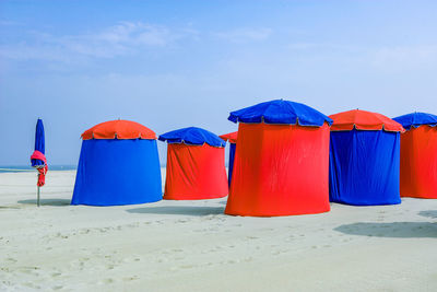 Multi colored umbrellas on beach against blue sky