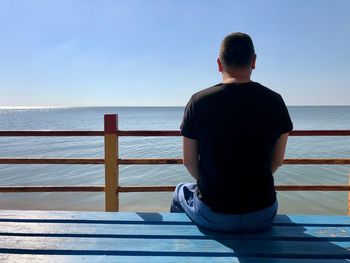 Rear view of man looking at sea against sky