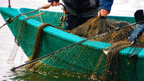 Midsection of fisherman fishing on boat in sea