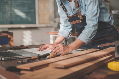 Midsection of man holding woman standing by wood