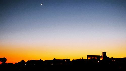 Silhouette buildings against clear sky at sunset