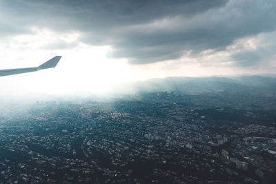 Aerial view of city buildings against cloudy sky