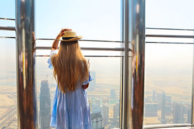 Rear view of woman looking through window