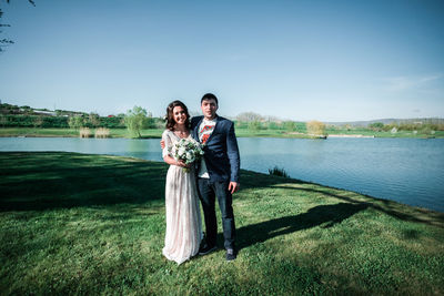 Full length of happy woman standing in lake against sky