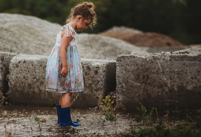 Girl standing against stone wall