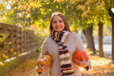 Portrait of smiling young woman standing against trees