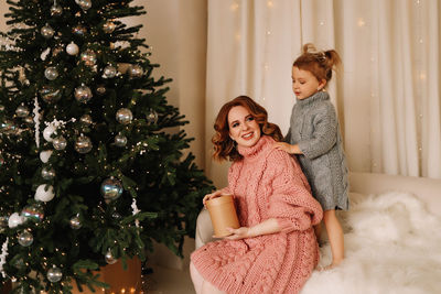 Portrait of young woman sitting on christmas tree