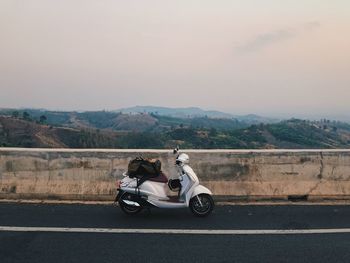 Man riding motorcycle on road against sky