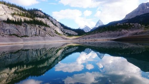 Scenic view of mountains reflecting in calm lake against sky
