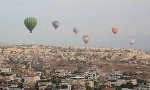 Hot air balloons flying over buildings against clear sky