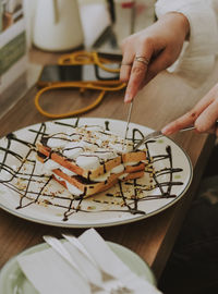 Cropped hand of woman eating sweet food on table