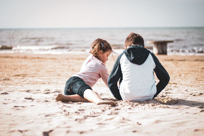 Siblings playing at beach during summer