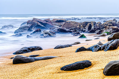 Scenic view of rocks on beach against sky