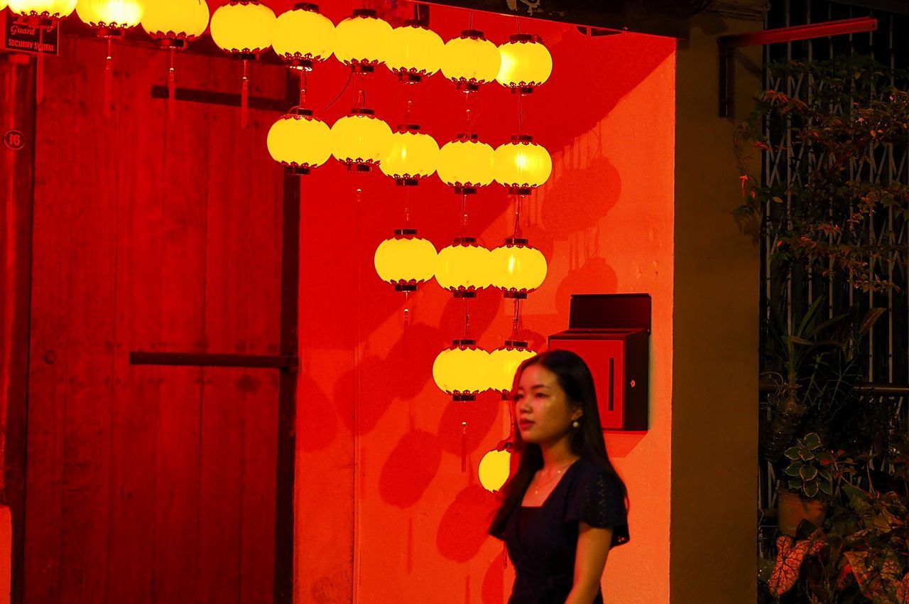 red, one person, women, standing, adult, person, architecture, young adult, lifestyles, entrance, night, female, communication, casual clothing, waist up, leisure activity, lighting equipment, outdoors, clothing, portrait, human face, child, door, emotion, illuminated, light, decoration, chinese lantern, stage