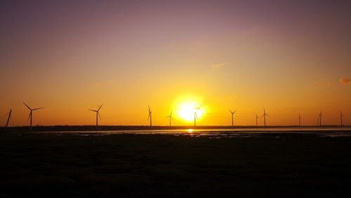 Silhouette of wind turbines on sea at sunset