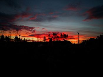 Silhouette landscape against dramatic sky during sunset