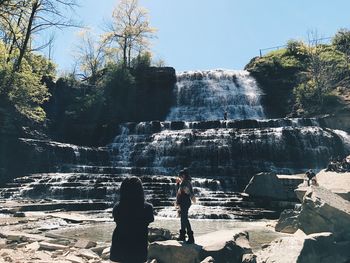 Friends standing against waterfall