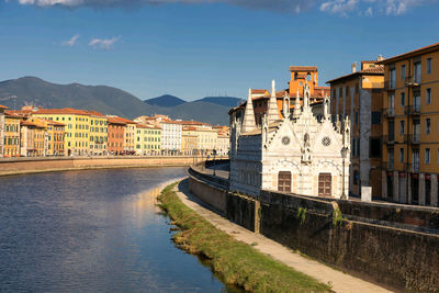 Buildings by river against sky