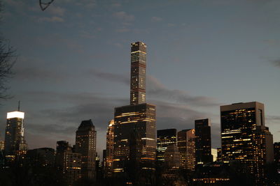 Low angle view of skyscrapers lit up against sky