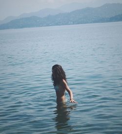 Beautiful woman standing in lake against mountains