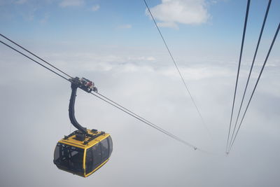 Low angle view of overhead cable cars against sky