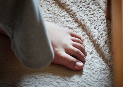 Low section of baby standing on rug