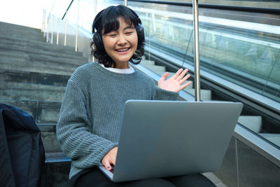 Portrait of young woman using laptop while sitting at airport