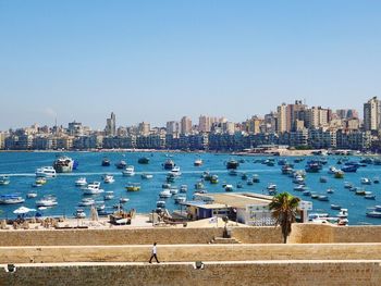 Boats in sea by buildings against clear sky