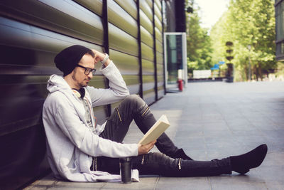 Side view of mature man reading book while sitting on road