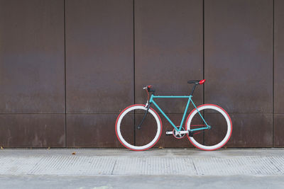 Bicycle parked on footpath against wall