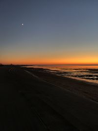 Scenic view of beach against clear sky during sunset