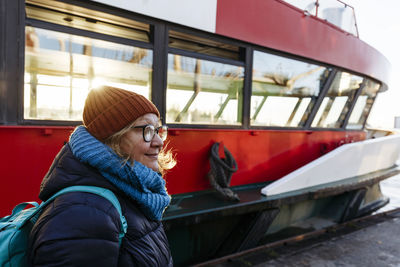 Senior woman in warm clothing standing by ferry