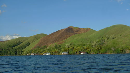 Scenic view of sea and mountains against blue sky