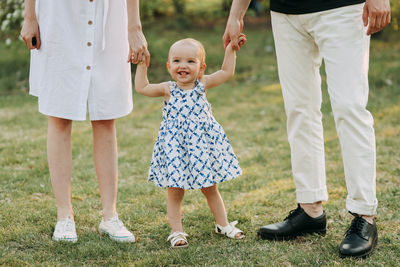A happy family with one small child walking together in the park in the summer outdoors