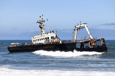 Abandoned ship in sea against sky