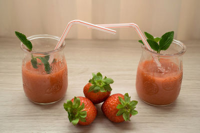 Two strawberry milkshakes in a glass with straws