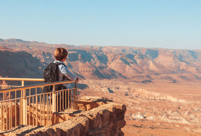 Rear view of a woman standing on mountain against clear sky in a desert