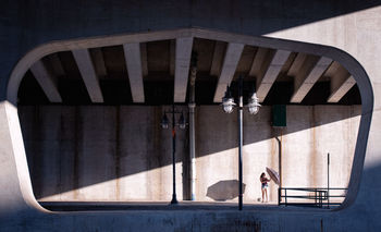 Woman with umbrella standing on sidewalk in city