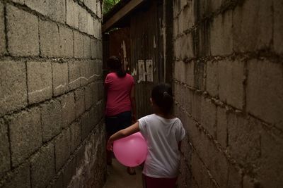 Rear view of siblings standing against wall