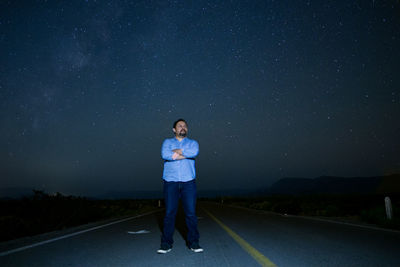 Full length of man standing on road against sky at night