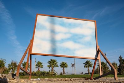 Low angle view of metallic structure on beach against blue sky